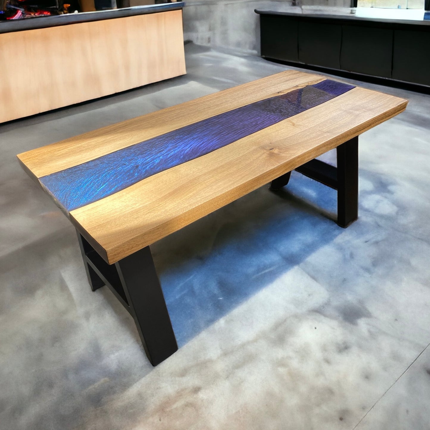 A large handcrafted coffee table featuring a chameleon color-shifting resin river that transitions between blue, green, and purple. The tabletop is made from rich walnut wood, paired with sturdy, powder-coated steel A-frame legs.