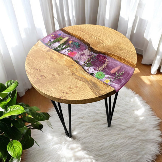 right side view of a floral oak and epoxy table, featuring real dried flowers set into a pink base colour, topped with clear resin. the table has black hairpin legs.