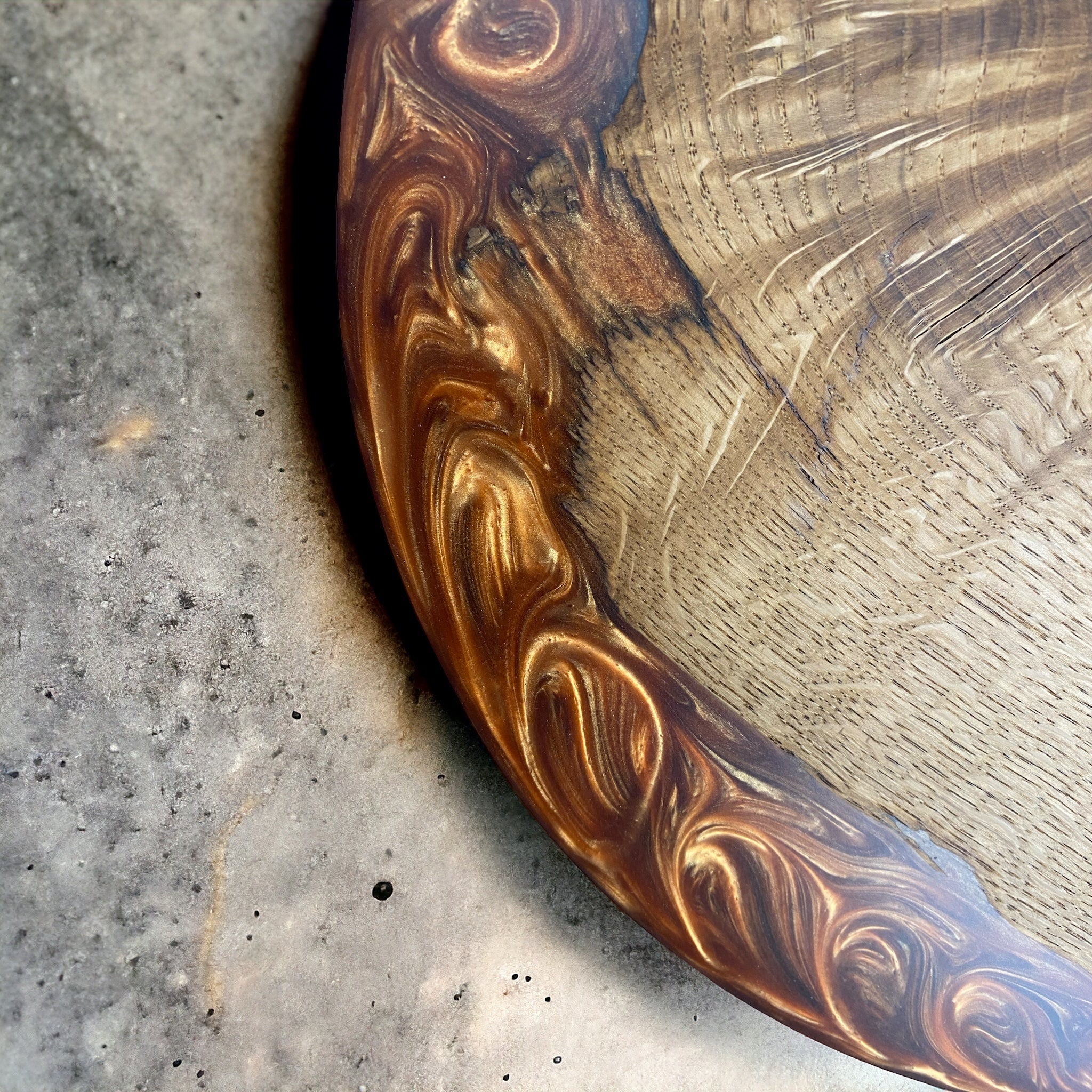 A detailed close-up of the oak tabletop, revealing intricate swirling copper resin merging with the wood’s rich grain patterns.