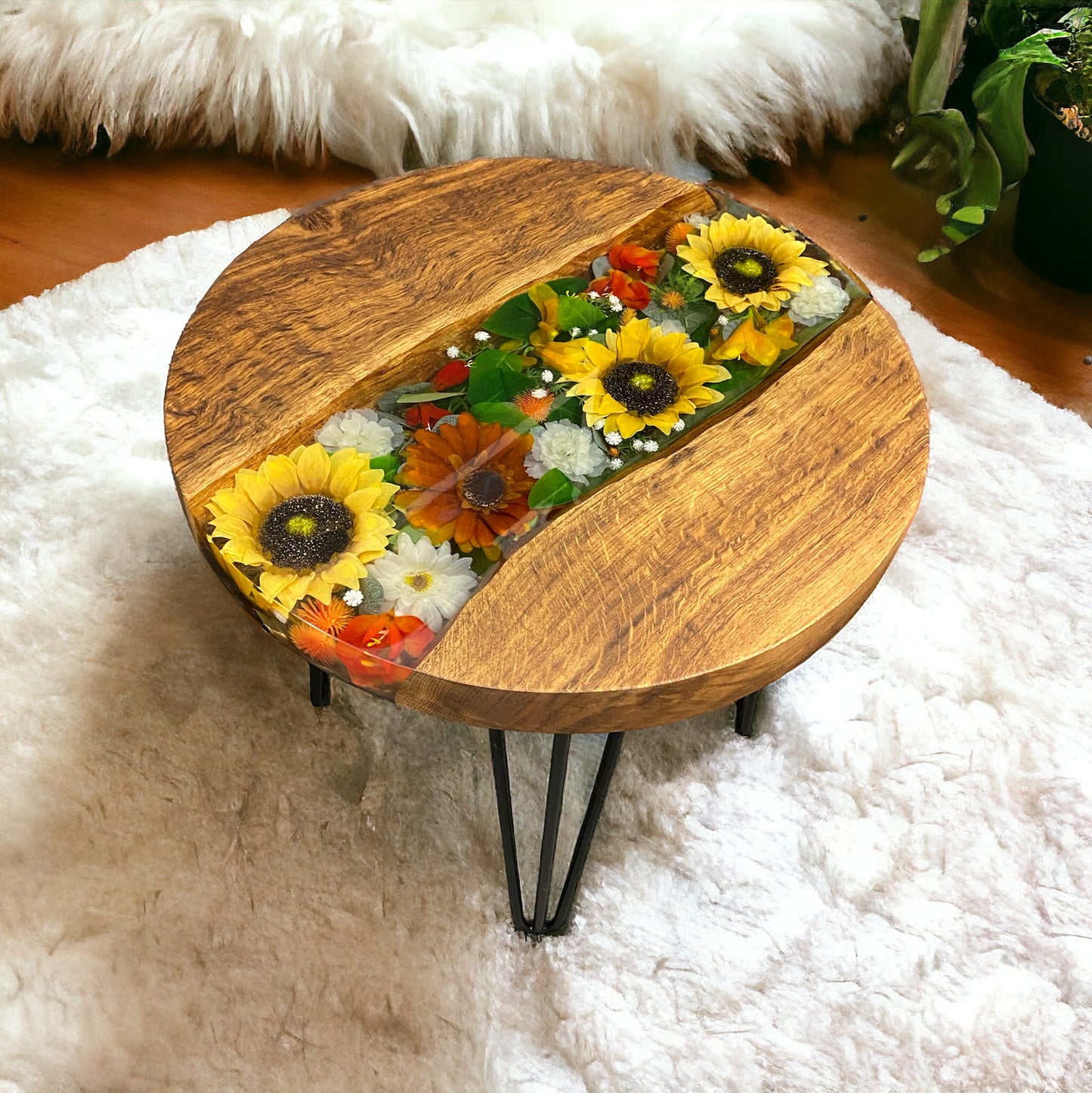 A round oak and epoxy resin coffee table. Featuring inlayed sunflowers and other flowers, covered with clear resin. supported by 4 black hairpin legs.