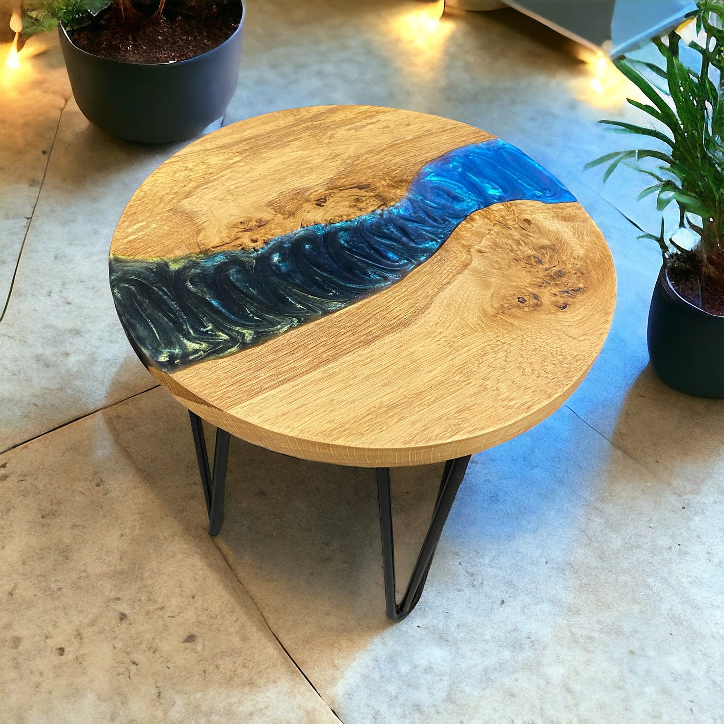 A handcrafted oak end table with a bold peacock-inspired epoxy resin flow, set on sturdy black hairpin legs for a modern touch.
