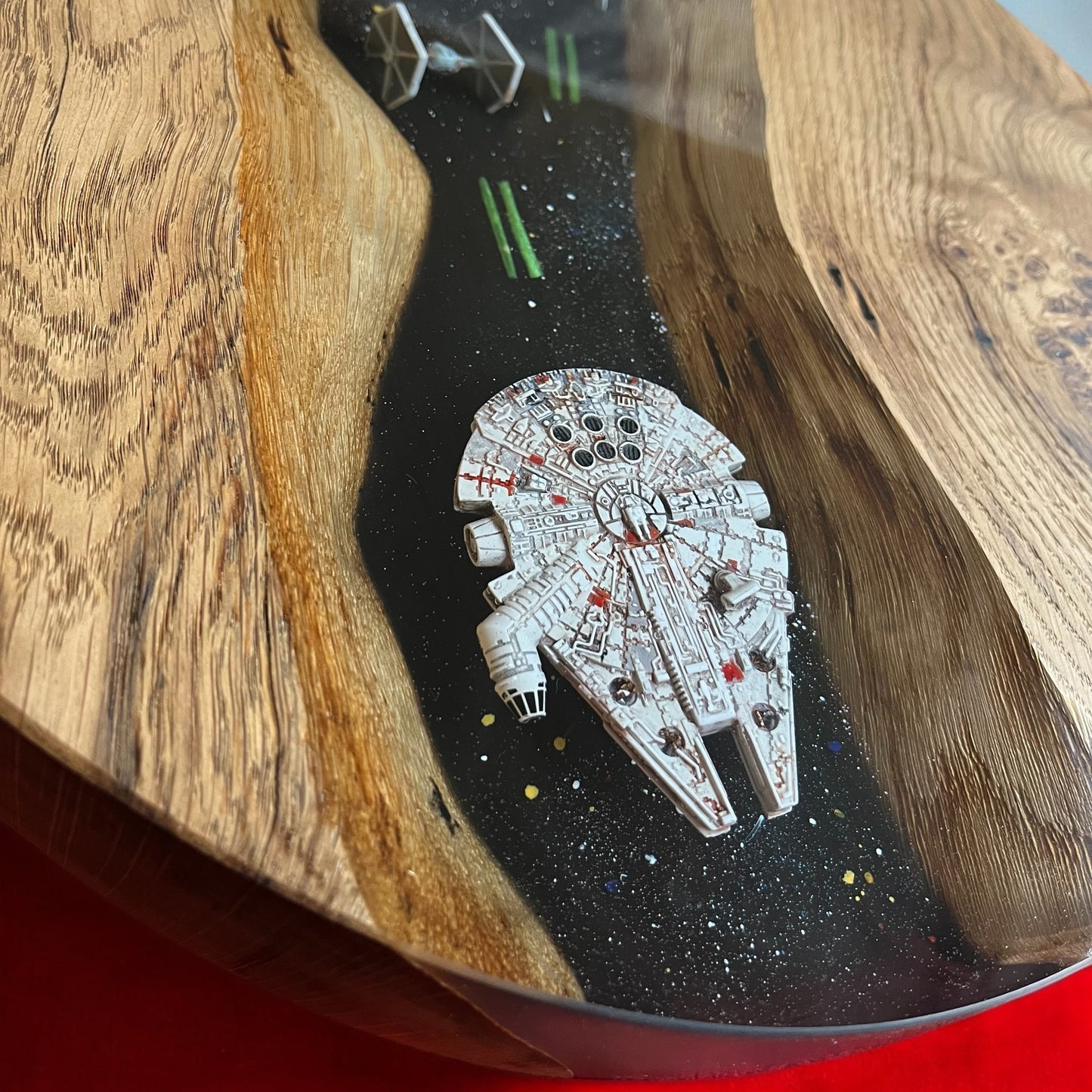 Close-up of the epoxy resin design on a Star Wars-themed oak end table, featuring detailed X-Fighters and the Millennium Falcon in a deep-space effect.