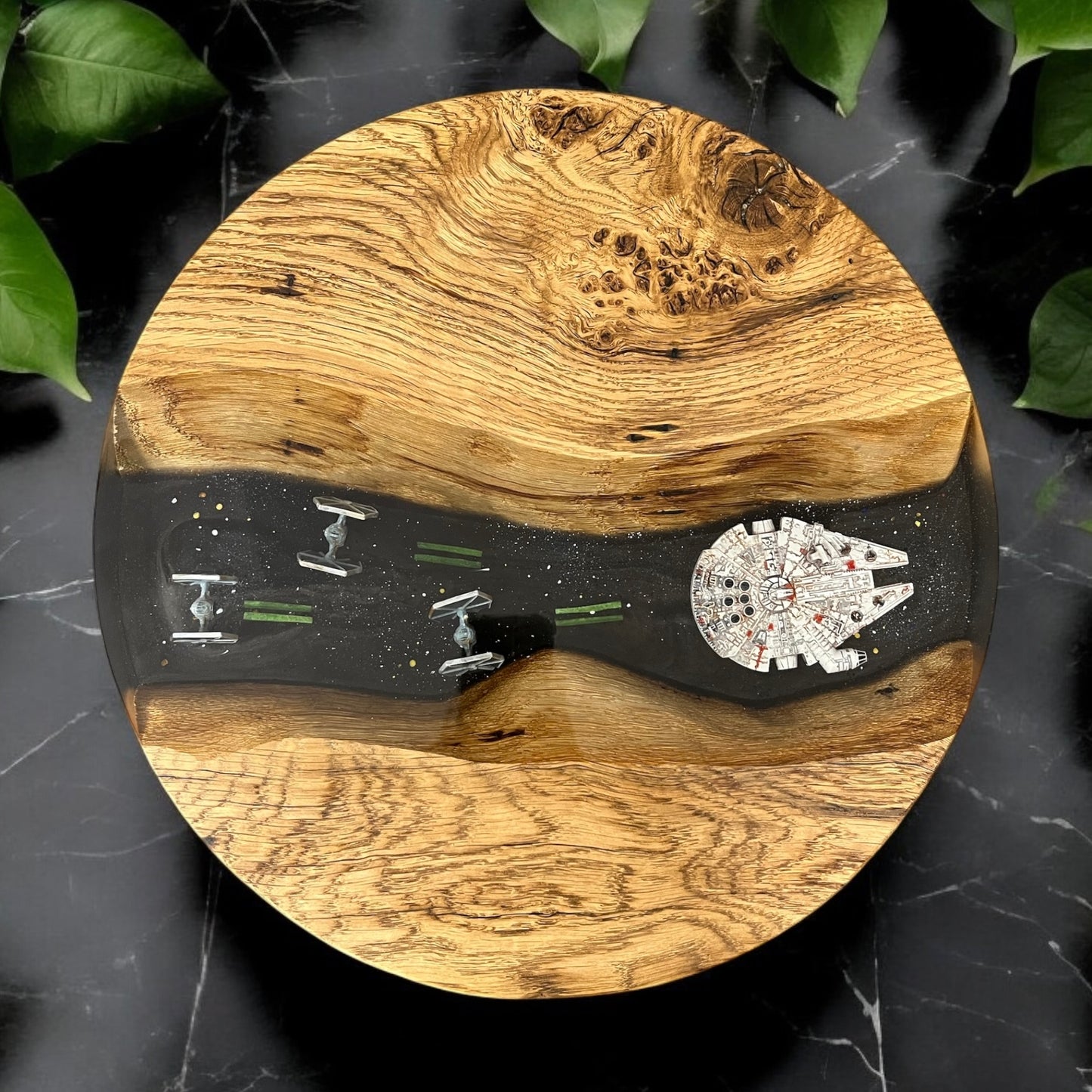 Overhead view of a handcrafted oak and epoxy resin end table featuring X-Fighters and the Millennium Falcon embedded in deep space-themed resin.