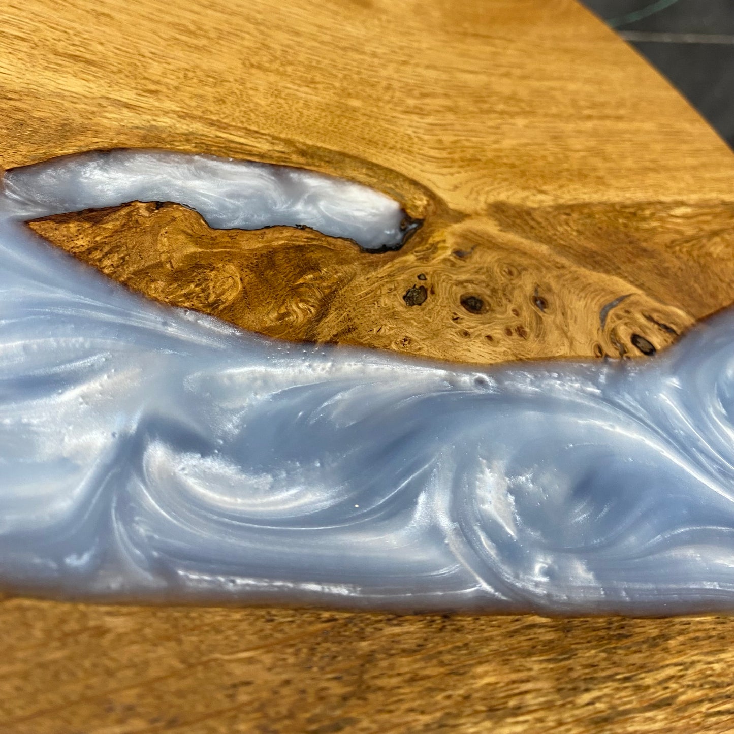 A detailed close-up of the oak and baby blue epoxy resin table top, showing the intricate wood grain and smooth, satin resin surface.