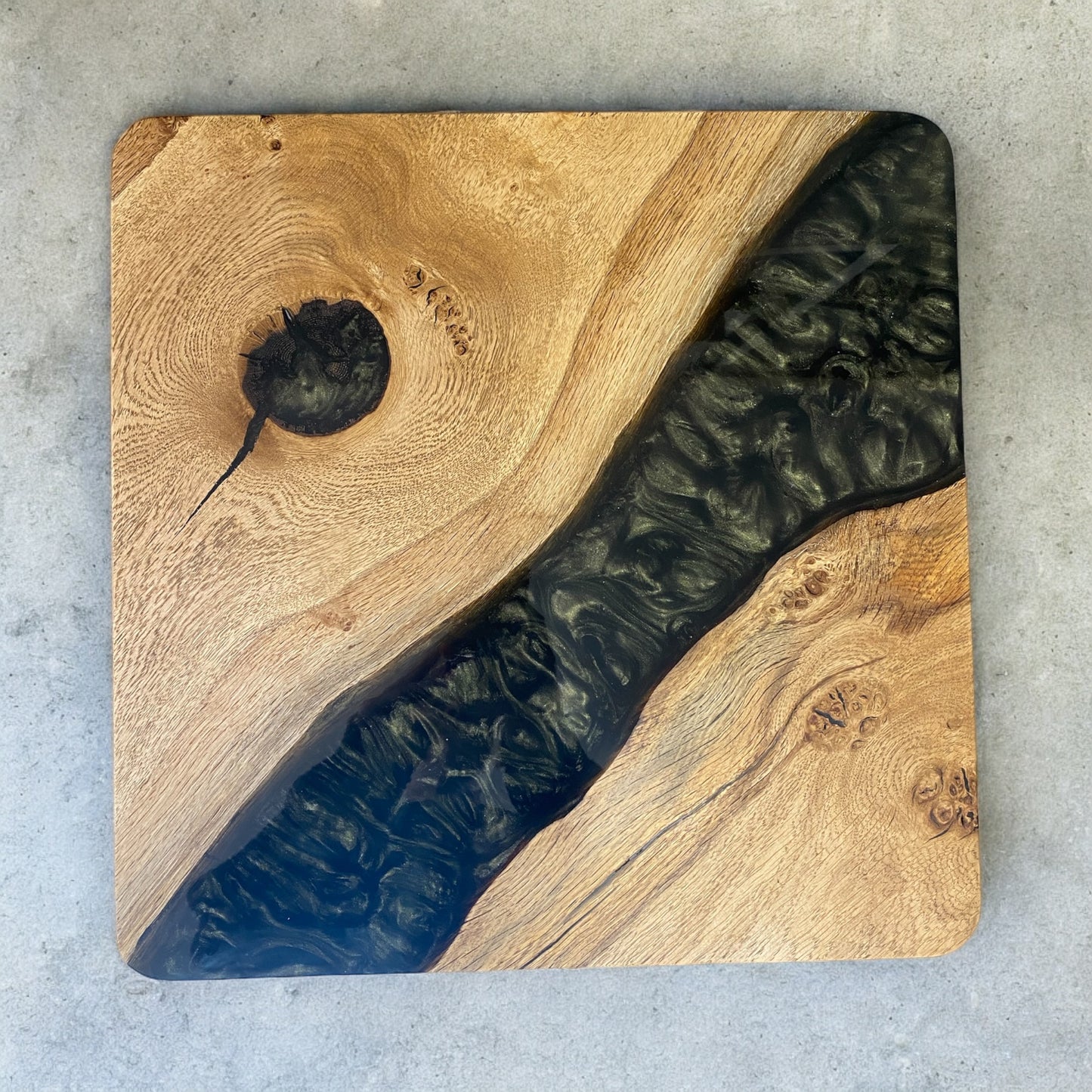 A top view of a resin river style table top featuring a diagonal black green resin river with an intense scale like pattern