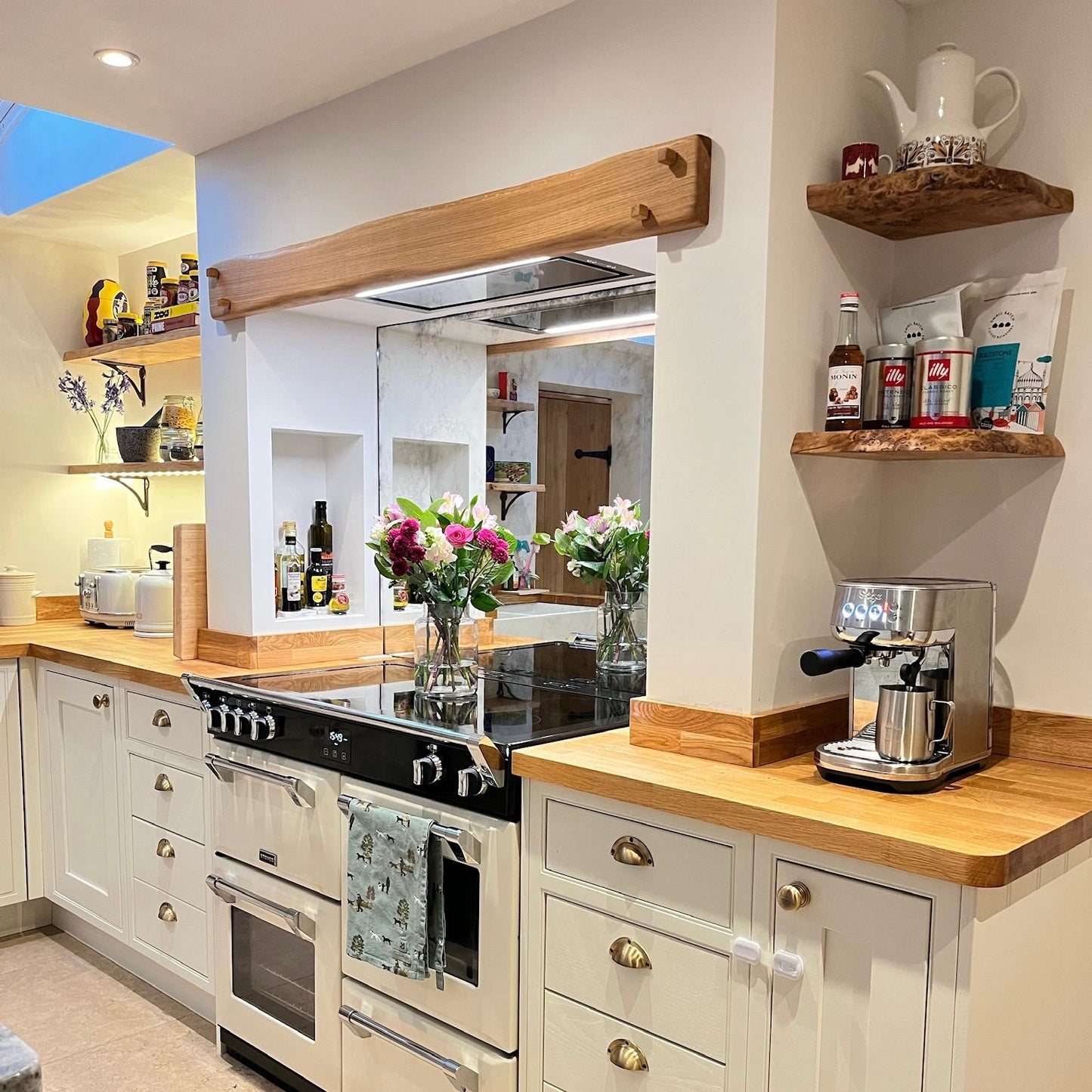 A beautiful farmhouse style kitchen featuring a handmade, solid oak mantle above a range cooker sat inside a chimney alcove.