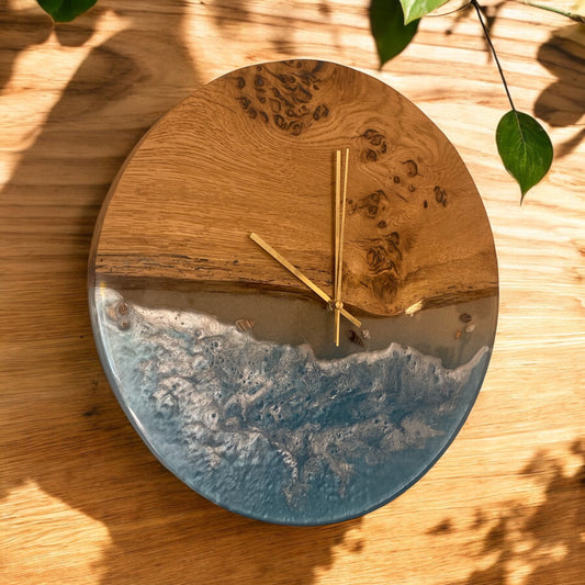 side view of a handmade oak and epoxy resin wall clock with a beach-inspired design, featuring ocean-like blue resin waves and elegant gold hands.