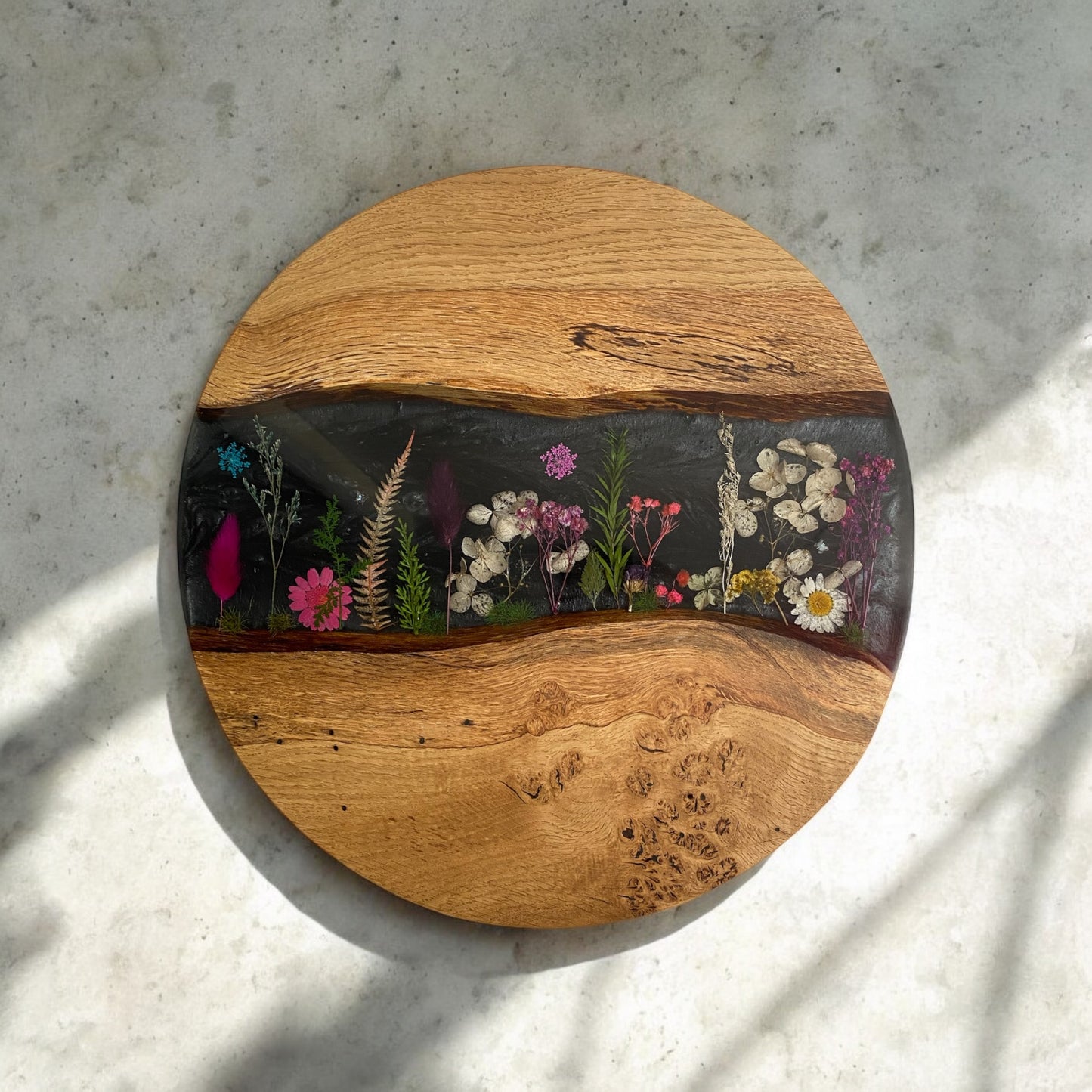Top-down view of a handcrafted oak and epoxy resin end table featuring an elegant black floral design embedded in the resin surface.