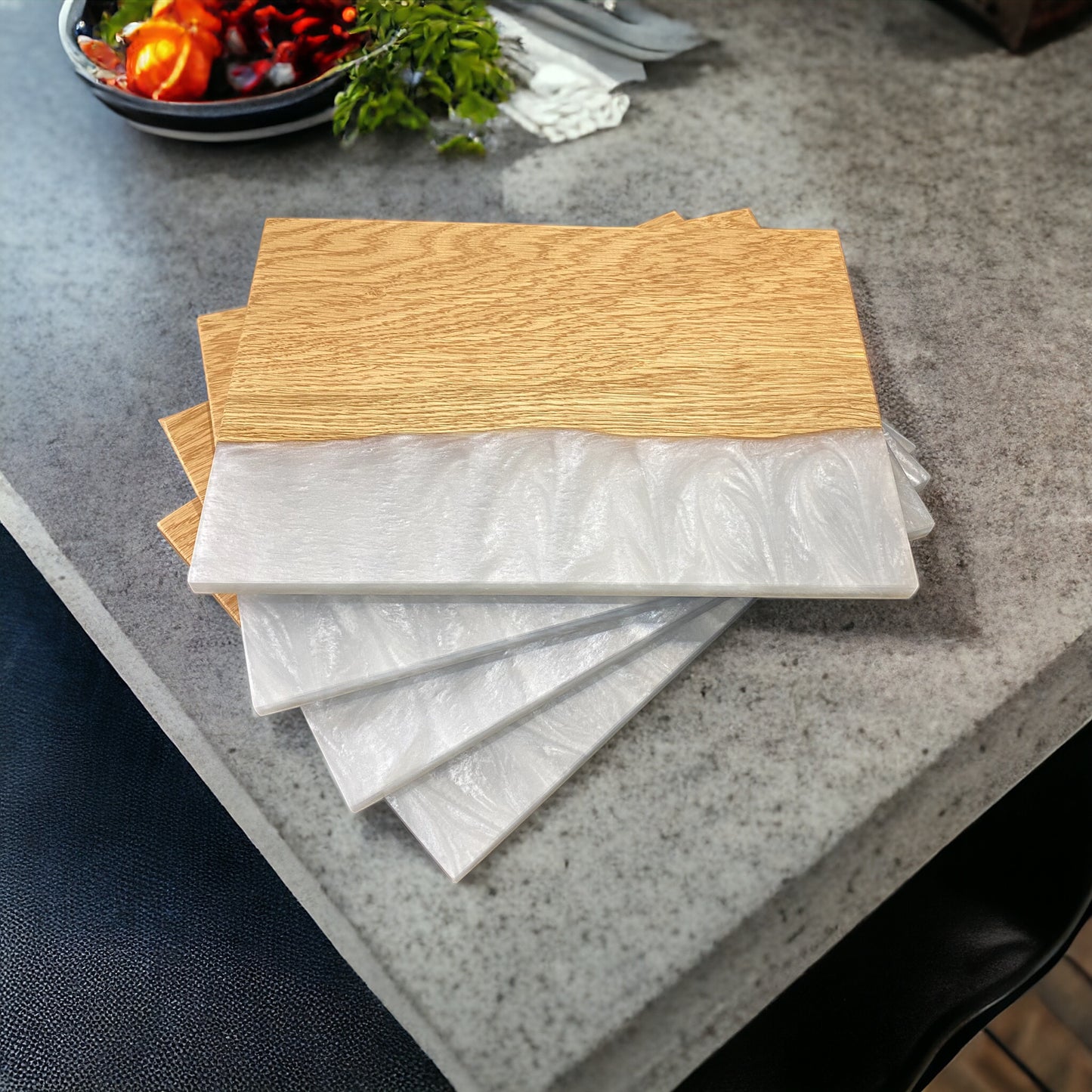 a set of 4 oak and resin placemats in a shade of white resin stacked in a spiral on a granite worktop