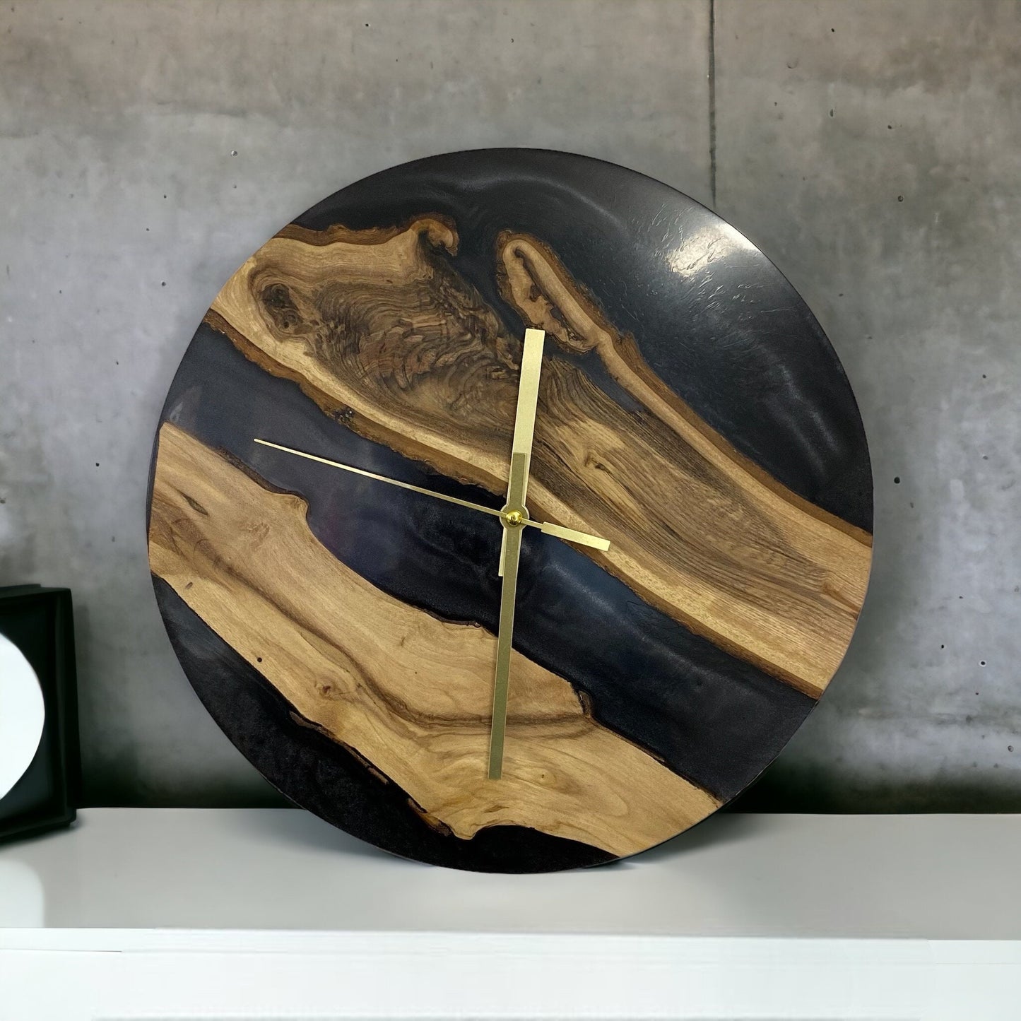 A black resin wall clock with gold hands