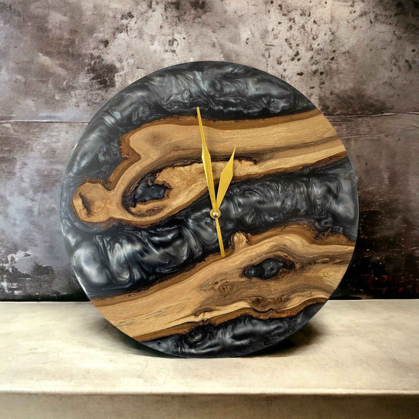 a silver grey oak and epoxy resin wall clock, with swirling detail in the resin. the clock features gold hands.