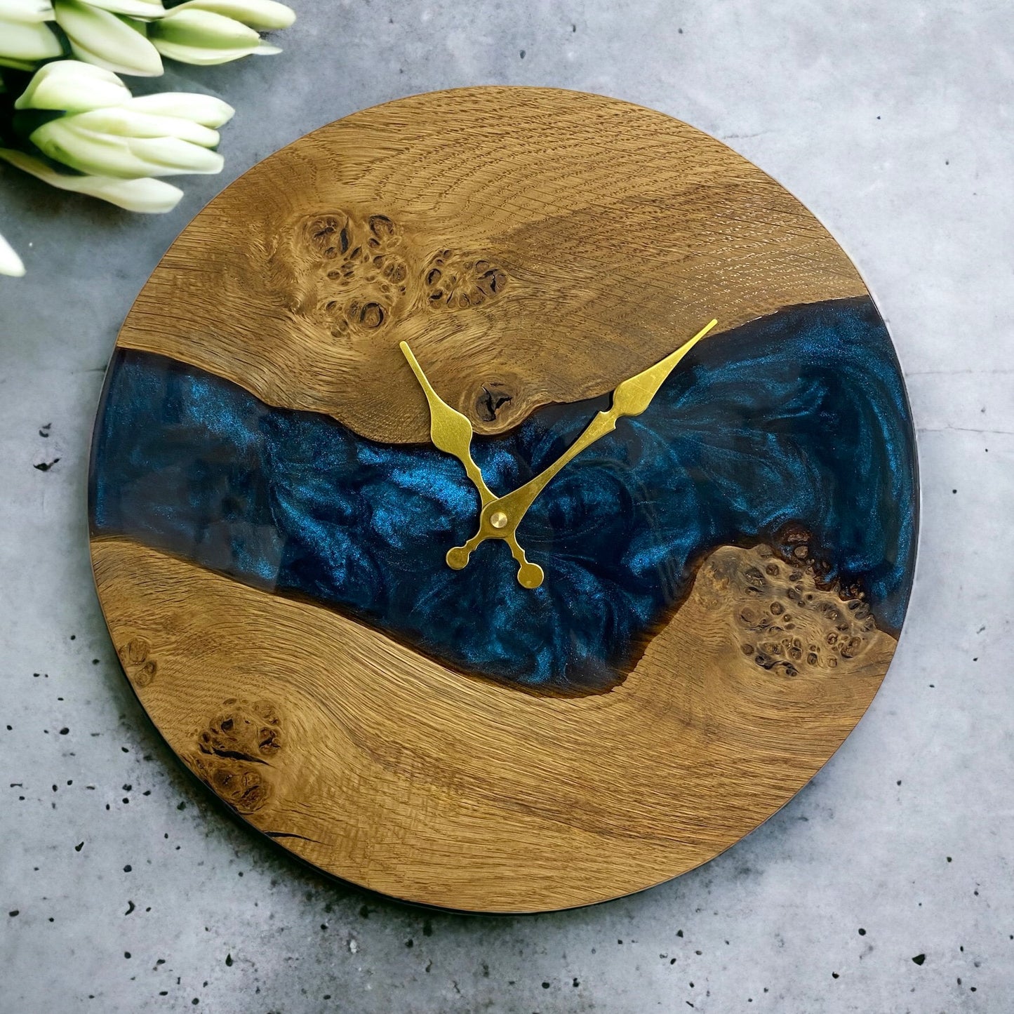 a oak and resin clock with gold hands, the resin is a deep blue in a river design.