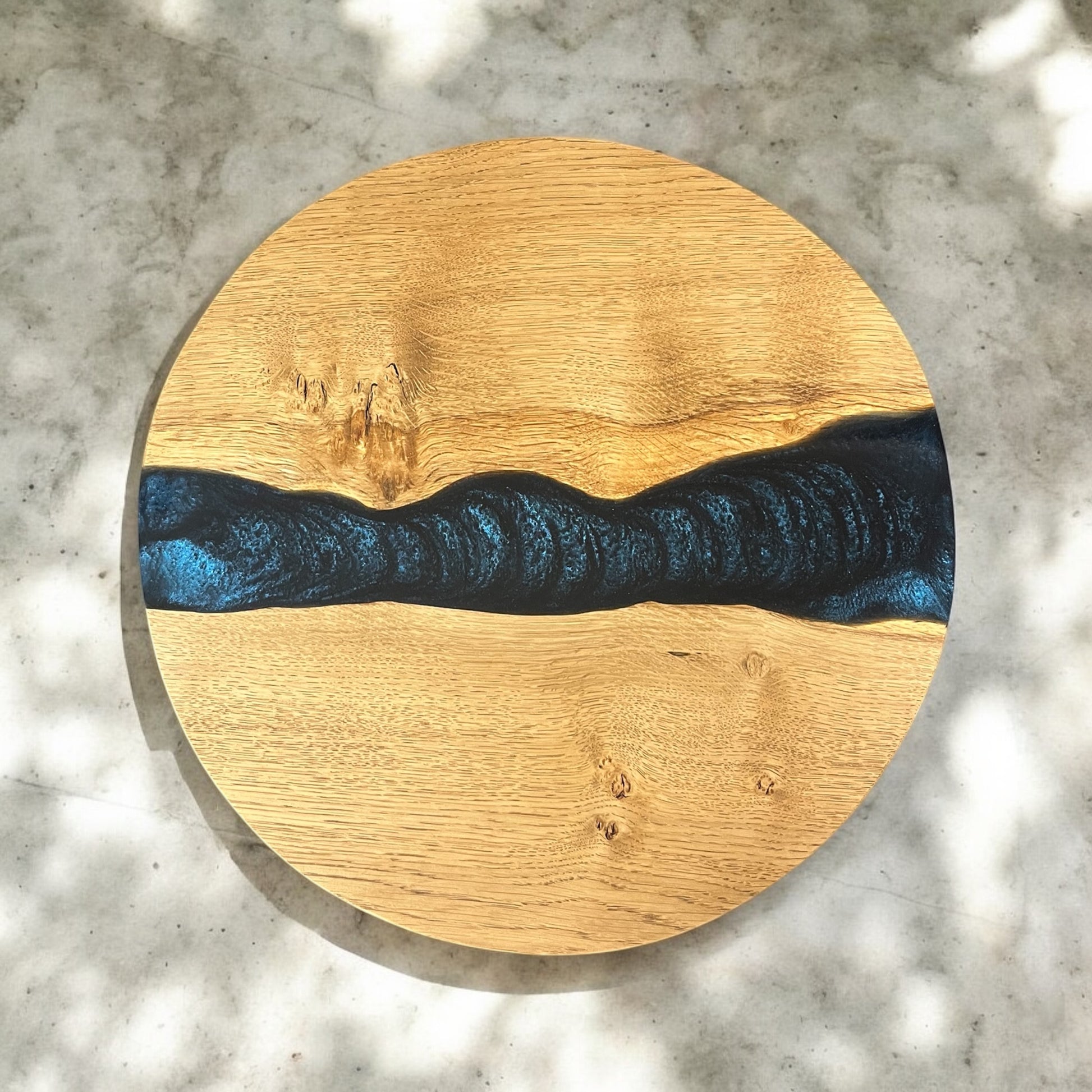 Top-down view of an oak and epoxy resin end table, featuring a deep astral blue resin river flowing through the wood, reminiscent of a starry night sky.